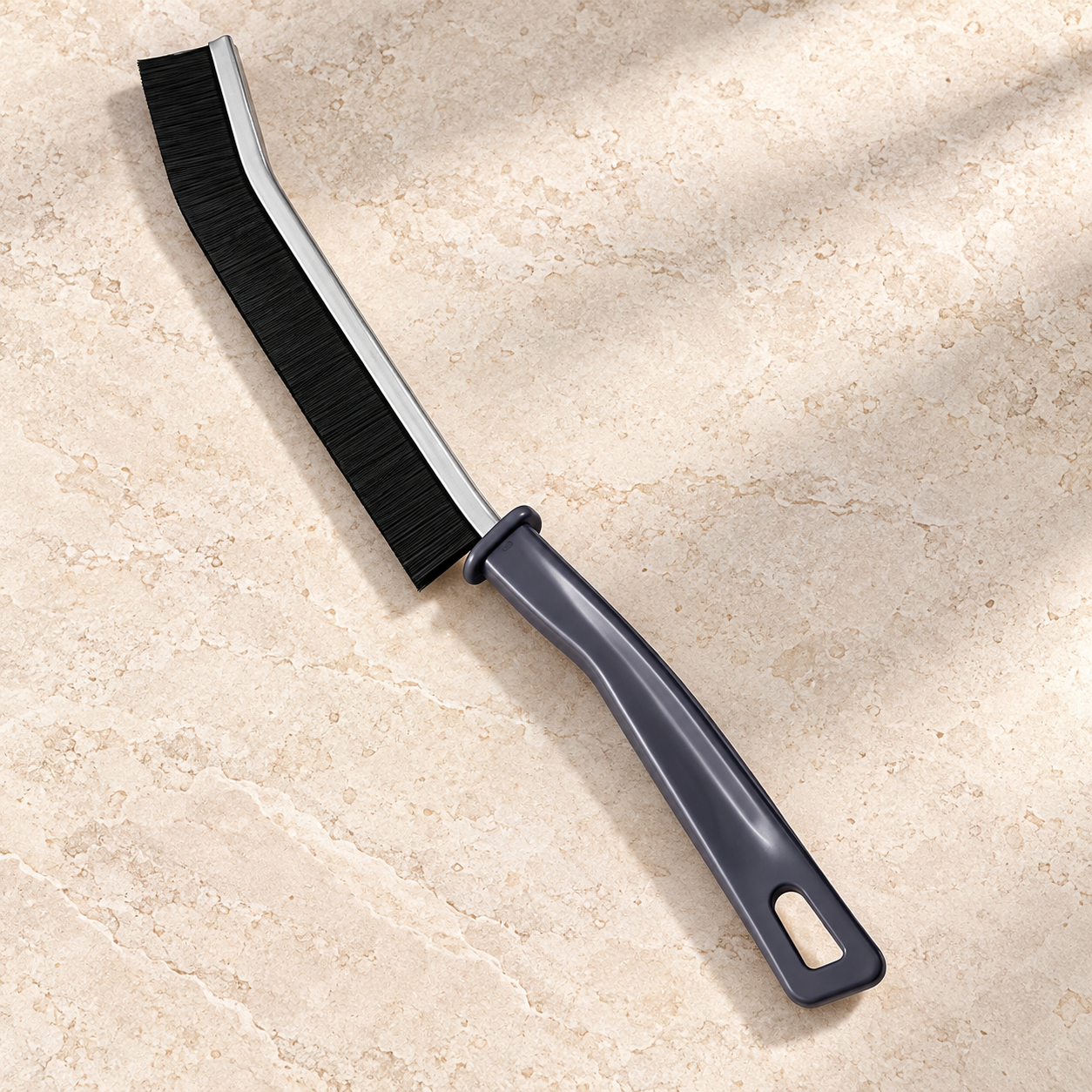 Grey-handled manual grout brush with black bristles