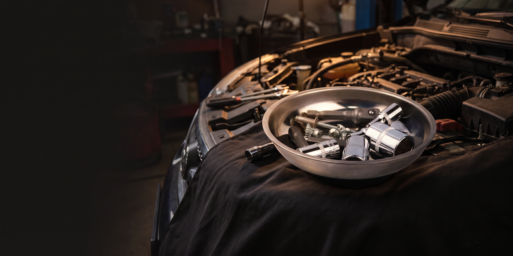 Magnetic parts tray holding bolts beside an open engine bay