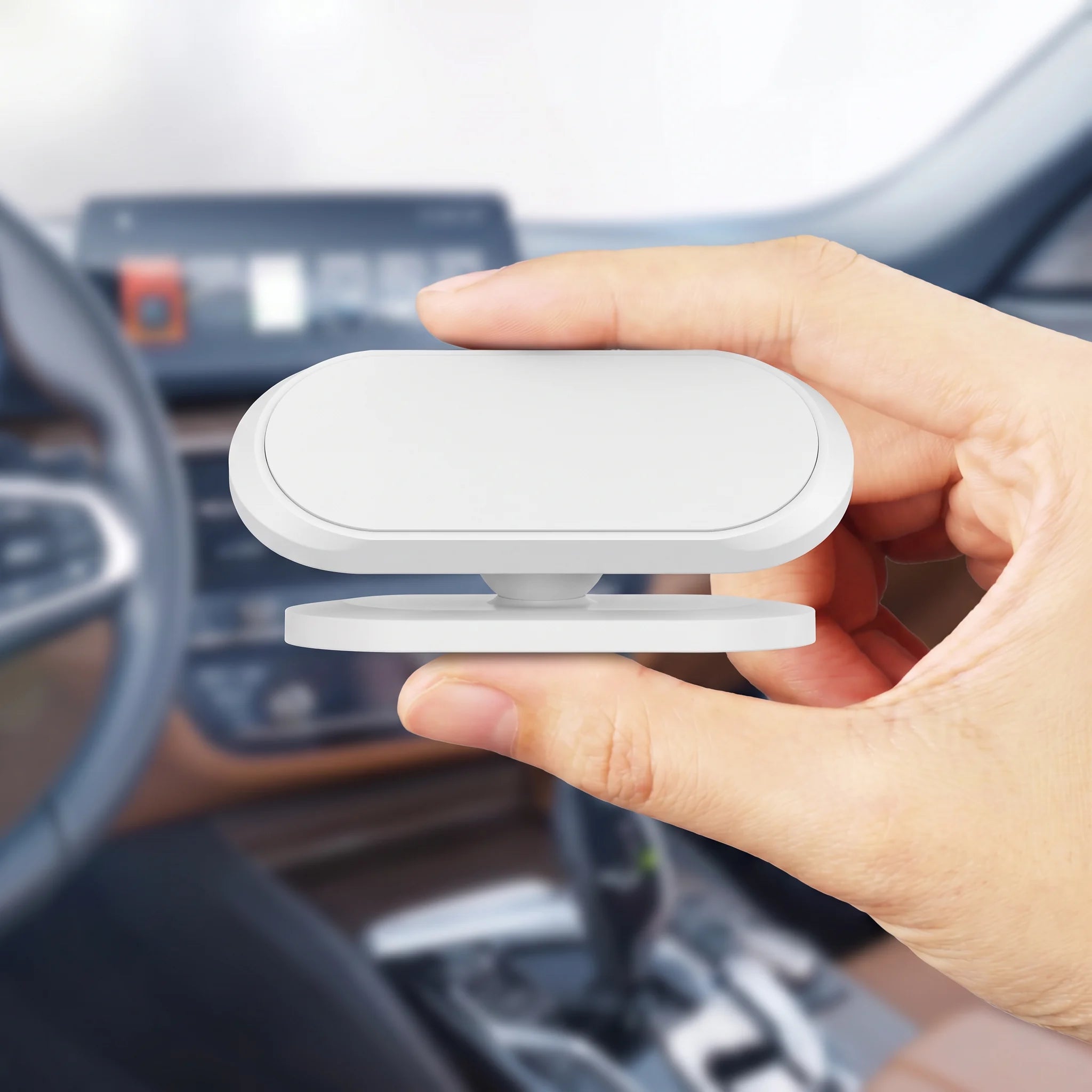 Compact white magnetic phone mount held in one hand