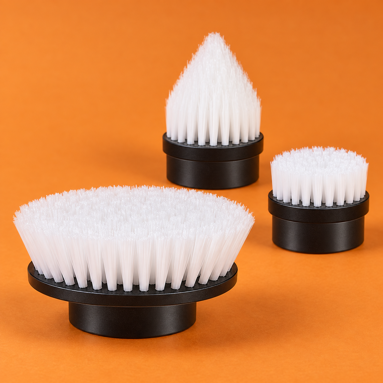 Close-up of large flat, small flat and pointed white-bristle brushes with black bases
